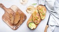 Gourmet lunch with avocado salmon toasts on rye bread and rose wine glasses, gray table background, top view