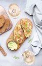 Gourmet lunch with avocado salmon toasts on rye bread and rose wine glasses, gray table background, top view