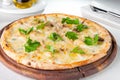 Gourmet pizza with gorgonzola and porcini white mushrooms decorated with parsley leaves on the wooden board on the served Royalty Free Stock Photo