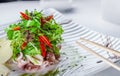 Gourmet salad with octopuses, arugula and vegetables on a white plate and chopsticks for foods