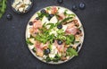 Gourmet salad with sweet pears, blueberries, blue cheese, smoked pork ham? arugula and walnuts. Black table background, top view Royalty Free Stock Photo