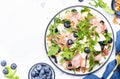 Gourmet salad with sweet pears, blueberries, roquefort cheese, smoked pork ham, arugula and walnuts. White table background, top Royalty Free Stock Photo