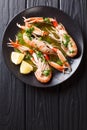 Gourmet seafood scampi or langoustine or Norway lobster are served on a black plate with sauce and lemon. Vertical top view Royalty Free Stock Photo