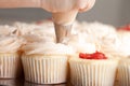 Gourmet strawberry filled cupcakes with frosting - being piped by a chef