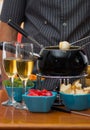 Gourmet Swiss fondue dinner with assorted cheeses and a heated pot of cheese fondue, man holding with a fork dipping a Royalty Free Stock Photo