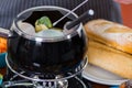 Gourmet Swiss fondue dinner with assorted cheeses and a heated pot of cheese fondue, man holding with a fork dipping a Royalty Free Stock Photo