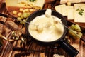 Gourmet Swiss fondue dinner on a winter evening with assorted cheeses on a board alongside a heated pot of cheese fondue with two Royalty Free Stock Photo