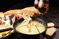 Gourmet Swiss fondue dinner on a winter evening with assorted cheeses on a board alongside a heated pot of cheese fondue with two Royalty Free Stock Photo