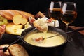 Gourmet Swiss fondue dinner on a winter evening with assorted cheeses on a board alongside a heated pot of cheese fondue with two Royalty Free Stock Photo