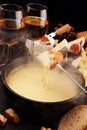 Gourmet Swiss fondue dinner on a winter evening with assorted cheeses on a board alongside a heated pot of cheese fondue with two Royalty Free Stock Photo