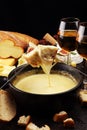 Gourmet Swiss fondue dinner on a winter evening with assorted cheeses on a board alongside a heated pot of cheese fondue with two Royalty Free Stock Photo