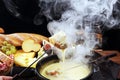 Gourmet Swiss fondue dinner on a winter evening with assorted cheeses on a board alongside a heated pot of cheese fondue with two Royalty Free Stock Photo