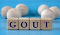 GOUT - word on wooden cubes on a blue background with wooden round balls