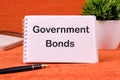 Government Bonds text on a blank sheet of notepad, there is a calculator, a pen and a flower in the background Royalty Free Stock Photo