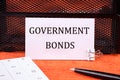 Government Bonds text on a white card next to the calculator, a pen on an orange background Royalty Free Stock Photo