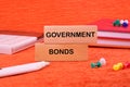 Government Bonds text on a wooden block on an orange background next to office supplies Royalty Free Stock Photo