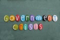 Government crisis, creative text composed with multi colored stone letters over green sand