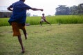 A small kid playing football and trying to hold the flying football kicked off by another child.