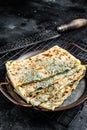 Gozleme Turkish flatbread with greens and cheese. Black background. Top view