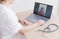 Gp hosts an online appointment with an elderly quarantined patient at home. Female doctor at the desk talking to an