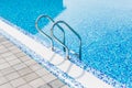 Grab bars ladder in the blue swimming pool. Summer. Royalty Free Stock Photo