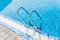 Grab bars ladder in the blue swimming pool. Summer. Royalty Free Stock Photo