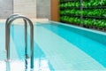 Grab bars ladder in the blue swimming pool, Swimming pool with stair and wooden deck at hotel. Royalty Free Stock Photo