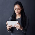 Grab some social networking apps to stay in contact. Studio shot of a young woman using her tablet against a grey Royalty Free Stock Photo