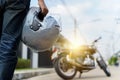 a young man riding a motorbike through the city. Rear view of a biker in a leather jacket with a chopper holding a helmet Royalty Free Stock Photo