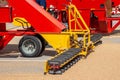 Grabbing grain from asphalt surface by scrapers of conveyor grain loader Royalty Free Stock Photo