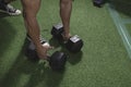 Grabbing a pair of 35 pound hex dumbbells from the gym floor, about to do a set of bent over rows. Fitness and bodybuilding
