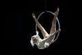 Graceful aerial acrobat doing her performance with a hoop isolated on black