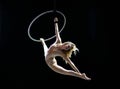 Graceful aerial acrobat doing her performance with a hoop isolated on black