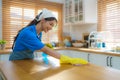 Asian female housewife using table cloth and sprayer in kitchen at home Royalty Free Stock Photo