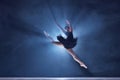 Graceful, attractive young woman, professional ballerina making performance, dancing on stage ever blue background with Royalty Free Stock Photo