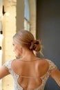 Graceful back of the bride. Looking out the window.Hairstyle - elegant bunch in the French style.