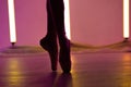 Graceful ballerina is dancing a classical ballet in white pointe shoes against a background of bright neon lights Royalty Free Stock Photo