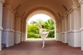 A graceful ballerina girl poses in an ancient street architectural arch. The beauty of an artistic dancer in a light lace dress, a