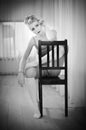 Graceful ballerina resting on chair. Black and white portrait of gorgeous ballet dancer sitting. Blonde ballerina relaxing Royalty Free Stock Photo