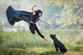 Graceful ballet boy in a black leather jacket sitting jumping with big black dog