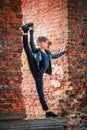 Graceful ballet boy in  black leather jacket stands on a ruined brick wall Royalty Free Stock Photo