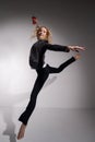 Graceful barefoot ballerina in a business suit jumping with a glass of coffee in her hands on a white background.