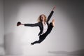 Graceful barefoot ballerina in a business suit jumping with a glass of coffee in her hands on a white background.