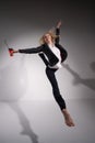 Graceful barefoot ballerina in a business suit jumping with a glass of coffee in her hands on a white background.