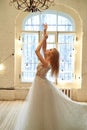 A graceful bride in a lace dress pulls her hands up.Room in loft style.