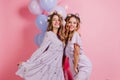 Graceful dark-haired ladies celebrating something and dancing with balloons. Studio photo of spectacular women in purple