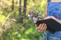 Graceful female hands hold a book and a bouquet of forest flowers. Copy space Royalty Free Stock Photo