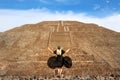 Graceful girl in a black dress and bandana with skulls on the background pyramid of the Sun in Teotihuacan.
