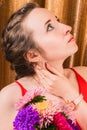 Graceful girl with bouquet of asters on background of a golden curtain