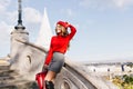 Graceful girl in gray skirt holding red backpack and smiling with eyes closed. Lovely slim woman in beret standing on